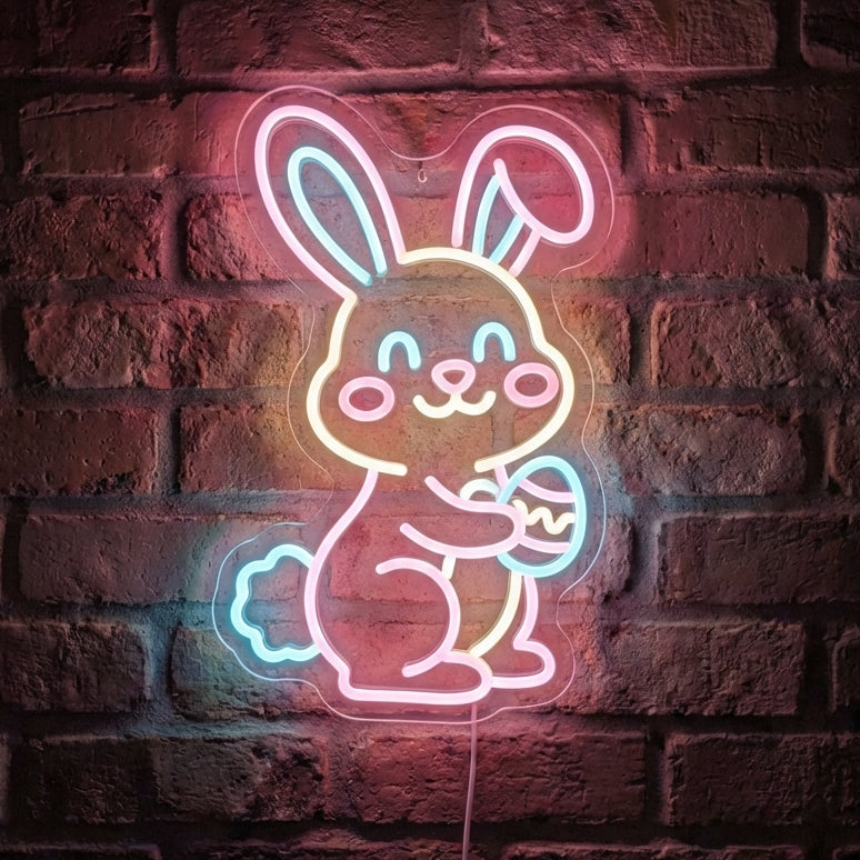 Bunny neon sign featuring a smiling Easter rabbit holding a decorated egg, glowing in pink, orange, and teal LED neon